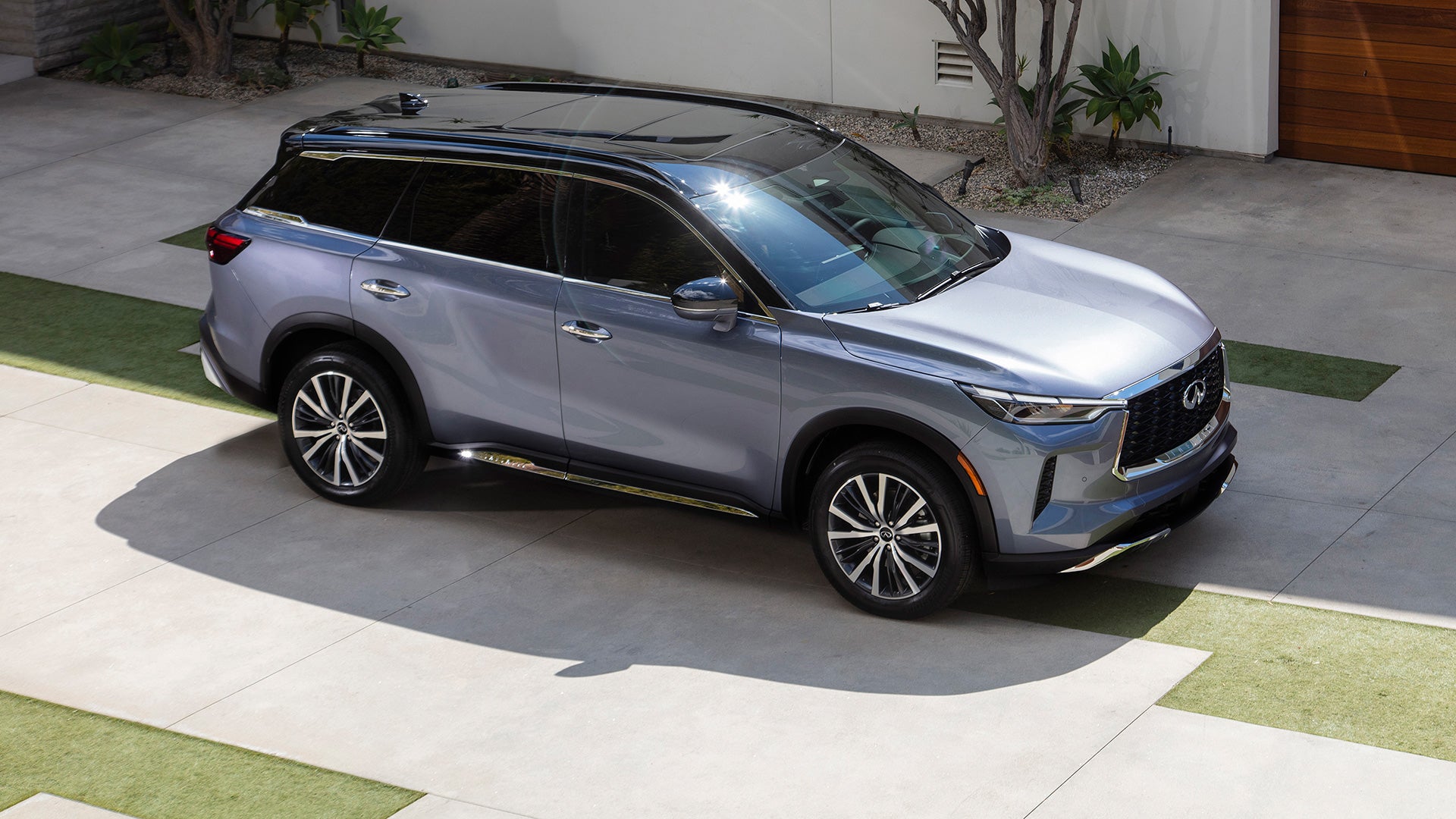 Silver Infiniti SUV parked in a modern driveway.